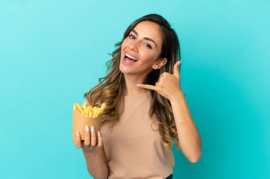 Kızarmış cipsleri izole edilmiş arka planda tutan genç bir kadın telefon jesti yapıyor. Bana geri dönüş işareti ver.