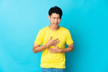 Genç Çinli bir adam mavi arka planda izole edilmiş, gülümsüyor.