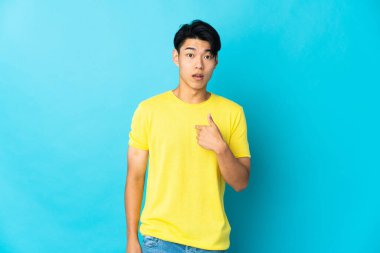 Mavi arka planda izole edilmiş genç bir Çinli kendini işaret ediyor.