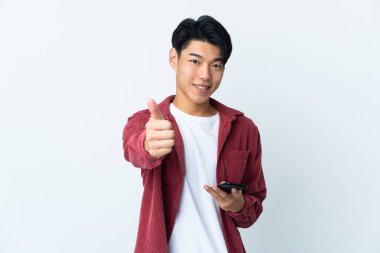 Genç Çinli adam beyaz arka planda izole edildi. Cep telefonuyla onay veriyor.