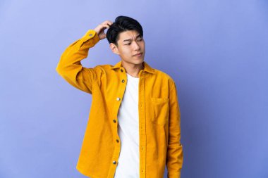 Mor arka planda izole edilmiş genç bir Çinli kafasını kaşırken şüpheleri var.