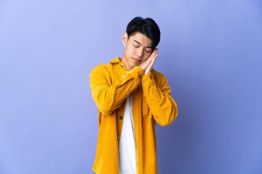 Mor arka planda izole edilmiş genç bir Çinli uyku jesti yapıyor.