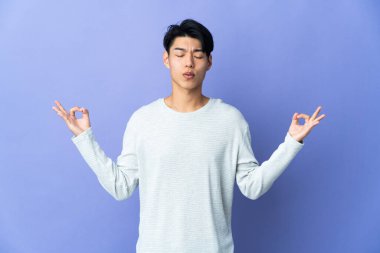 Mor arka planda Zen pozu almış genç bir Çinli.