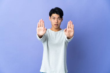 Mor arka planda izole edilmiş genç bir Çinli dur hareketi yapıyor ve hayal kırıklığına uğruyor.