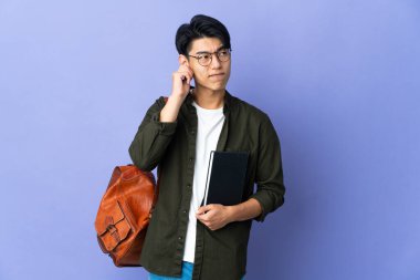 Mor arka planda izole edilmiş genç bir bayan hayal kırıklığına uğramış ve kulaklarını kapatmış.