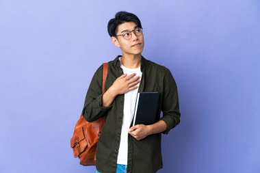 Mor arka planda izole edilmiş genç bir bayan gülümseyerek yukarı bakıyor.