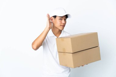 Çinli adam beyaz arka planda izole edilmiş bir şekilde bir şey dinlerken elini kulağına koyuyor.