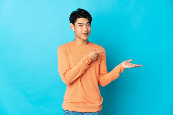 Νεαρός Κινέζος Απομονωμένος Μπλε Φόντο Κρατώντας Copyspace Φανταστικό Στην Παλάμη — Φωτογραφία Αρχείου