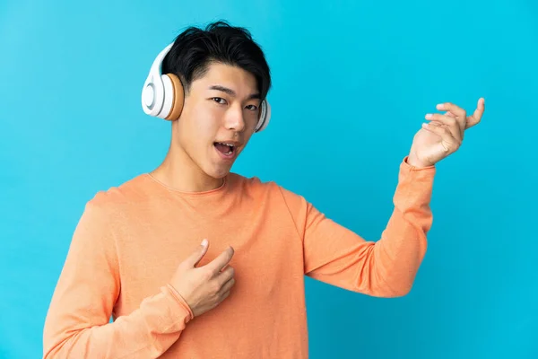 Young Chinese Man Isolated Blue Background Listening Music Doing Guitar — Stock Photo, Image