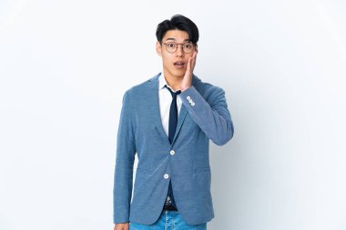 Genç Çinli iş adamı beyaz arka planda şaşırmış ve şok olmuş bir yüz ifadesiyle izole edilmiş.