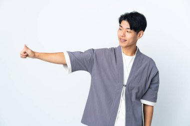 Beyaz arka planda izole edilmiş genç bir Çinli baş parmak hareketi yapıyor.