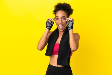 Genç Afrikalı sporcu kadın sarı arka planda gözlüklü ve şaşırmış.