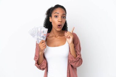 Genç Afrikalı Amerikalı bir kadın beyaz arka planda izole edilmiş bir sürü para alıyor. Çözümü bulmak için parmağını kaldırıyor.