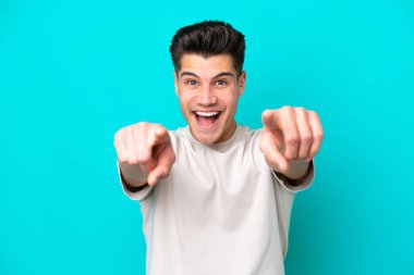 Genç, yakışıklı, beyaz bir adam mavi fırında izole edilmiş, şaşırmış ve ön tarafı işaret ediyor.