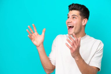 Genç, yakışıklı, beyaz bir adam mavi fırında izole edilmiş ve yüzünde sürpriz bir ifade var.