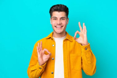 Genç, yakışıklı, beyaz bir adam, mavi bir bakkalda izole edilmiş, iki eliyle 