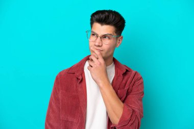 Genç, yakışıklı, beyaz bir adam mavi fırında tek başına, gözlüklü ve kuşkulu.