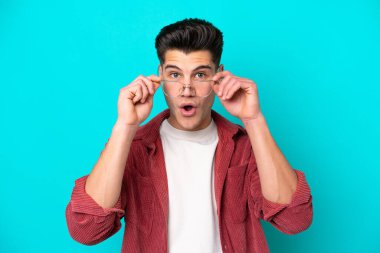 Genç, yakışıklı, beyaz bir adam mavi fırında tek başına, gözlüklü ve şaşkın bakışlı.