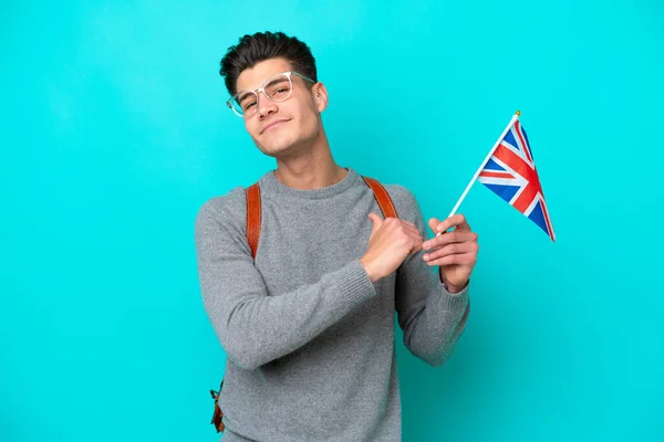 高举英国国旗的年轻的高加索人 因蓝色背景而被隔离 自豪而自鸣得意 — 图库照片