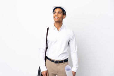 Miğferi olan ve elinde izole edilmiş beyaz arkaplan üzerinde planlar tutan Afrikalı Amerikalı mimar bir fikir ararken