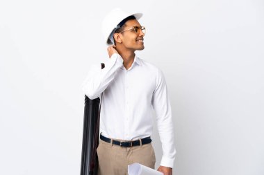 Kafasında miğferi olan ve izole edilmiş beyaz arkaplan üzerinde planları olan Afrikalı Amerikalı mimar bir fikir üretiyor.