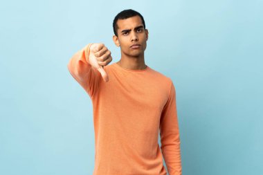 İzole edilmiş arka planda yaşayan Afro-Amerikalı bir adam olumsuz ifadeyle baş parmağını aşağı gösteriyor