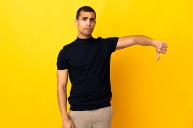 İzole edilmiş arka planda yaşayan Afro-Amerikalı bir adam olumsuz ifadeyle baş parmağını aşağı gösteriyor