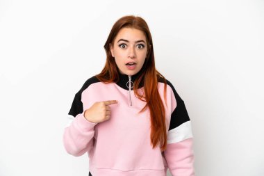 Beyaz arka planda izole edilmiş genç kızıl saçlı kadın kendini işaret ediyor.