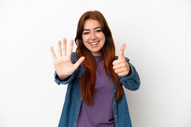 Beyaz arka planda izole edilmiş genç kızıl saçlı kadın parmaklarıyla altı kişi sayıyor.