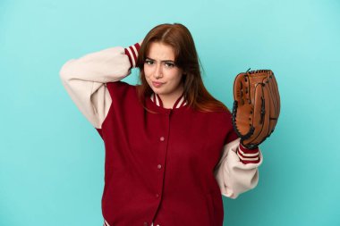 Beyzbol oynayan genç kızıl saçlı kadın mavi arka planda izole edilmiş, kuşkuları var.