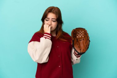 Beyzbol oynayan genç kızıl saçlı kadın mavi arka planda izole edilmiş, kuşkuları var.