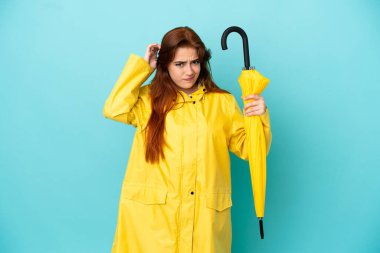 Mavi arka planda şemsiyesi olan kızıl saçlı kadının şüpheleri var.