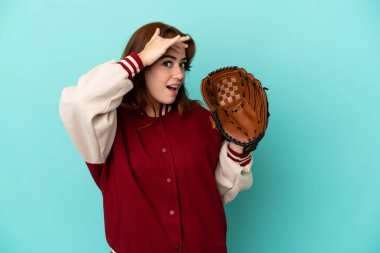 Beyzbol oynayan genç kızıl saçlı kadın, mavi arka planda soyutlanmış bir şekilde yan tarafa bakarken sürpriz jest yapıyor.