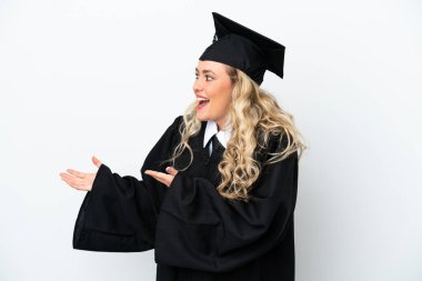 Üniversiteden mezun genç bir kadın beyaz arka planda izole edilmiş ve sürpriz bir ifadeyle yan tarafa bakıyor.