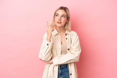 Pembe arka planda izole edilmiş beyaz bir kadın harika bir fikre işaret ediyor.