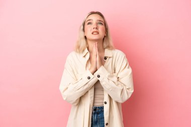 Pembe arka planda izole edilmiş genç beyaz kadın avuç içlerini bir arada tutuyor. İnsan bir şey ister.