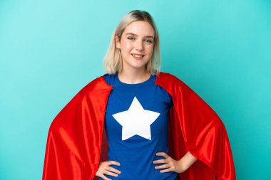 Süper kahraman beyaz kadın mavi arka planda izole edilmiş gülüyor.