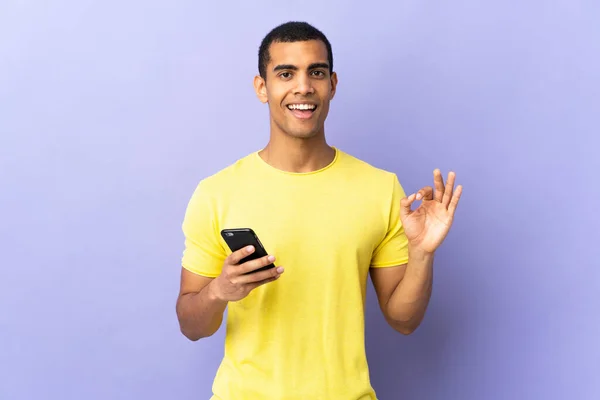 Hombre Afroamericano Sobre Fondo Púrpura Aislado Usando Teléfono Móvil Mostrando —  Fotos de Stock