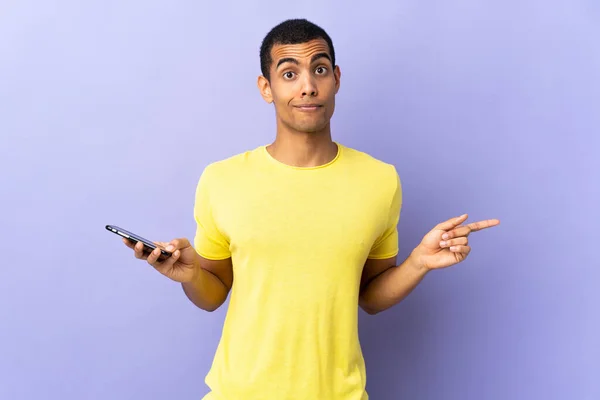 African American Man Isolated Purple Background Using Mobile Phone Pointing — 스톡 사진