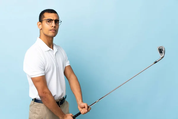 在孤立的蓝色背景上打高尔夫的非裔美国人 — 图库照片