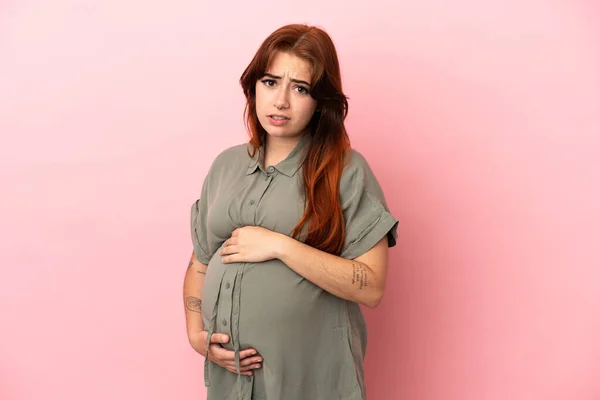 若いですRedhead Caucasian女性隔離上のピンクの背景妊娠 — ストック写真