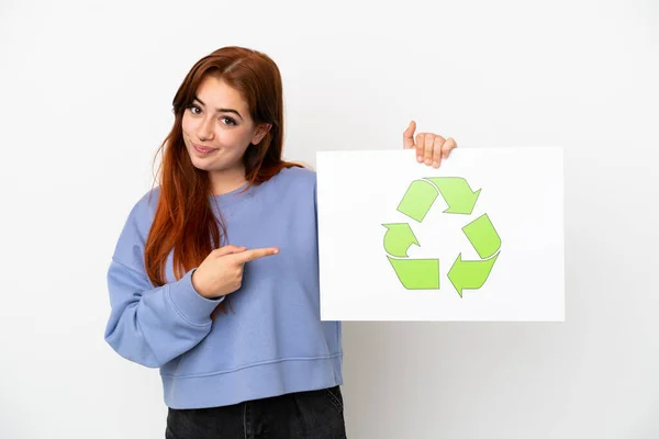 Młoda Ruda Kobieta Odizolowana Białym Tle Trzymająca Tabliczkę Ikoną Recyklingu — Zdjęcie stockowe