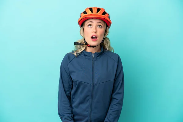 Genç Bisikletçi Kadın Mavi Arka Planda Izole Edilmiş Yukarı Bakıyor — Stok fotoğraf