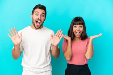 Mavi arka planda, şaşırmış ve şok olmuş bir yüz ifadesi olan genç bir çift.