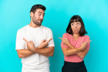 Mavi arka planda izole edilmiş genç çift, yan taraftakilerin şüphelerine işaret ediyor.