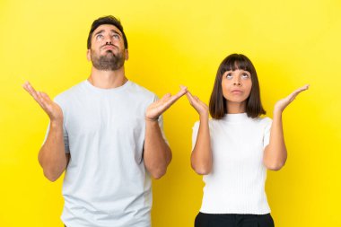 Sarı arka planda izole edilmiş genç çift kötü bir durum yüzünden hayal kırıklığına uğradı.