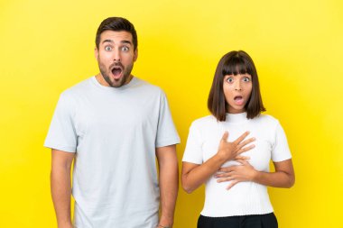 Sarı arka planda, şaşırmış ve şok olmuş bir yüz ifadesi olan genç bir çift.