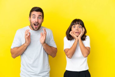 Sarı arka planda izole edilmiş genç çift sağa bakarken şaşırmış ve şok olmuştu.