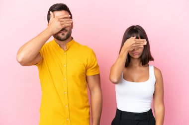 Pembe arka planda, gözleri elleriyle kaplayan genç bir çift. Bir şey görmek istemiyorum.