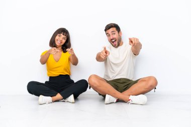Genç bir çift beyaz arka planda izole bir şekilde yerde oturuyor.